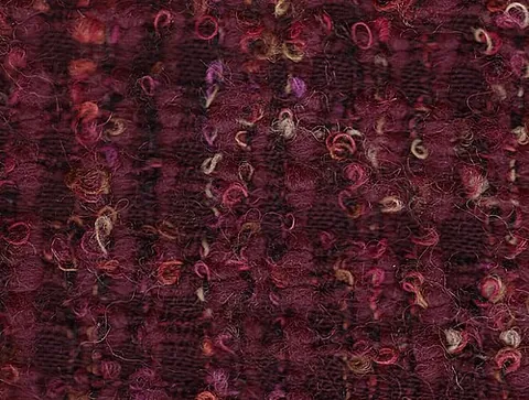 bouclé: a fabric knitted or woven of uneven yarn with a surface of loops and curls