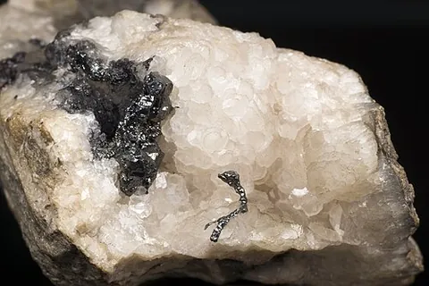 acanthite: a mineral form of silver sulfide, Ag₂S, that is a major ore of silver, that forms slender prisms