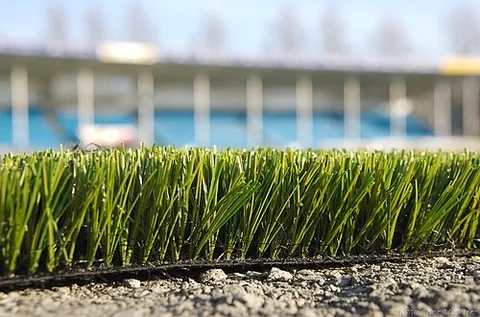 artificial turf: an artificial grass surface made to resemble real grass, often used for sports fields