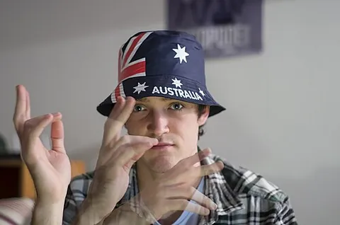 aussie salute: the act of waving a hand in front of the face to flick away flies (particularly bush flies, Musca...