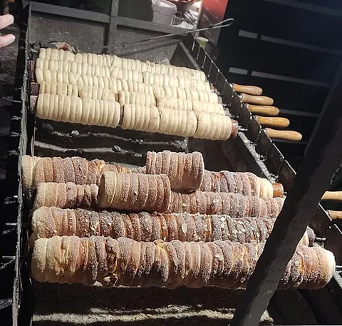 trdelník: a spit cake, variant of kürtőskalács, made from dough cooked while wrapped around a metal pin and...