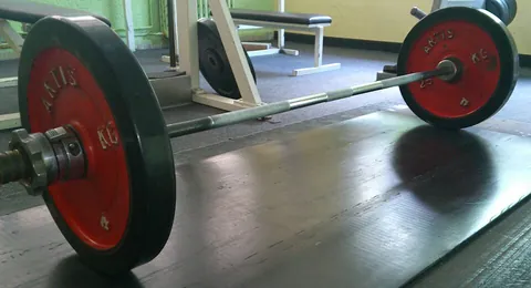 barbell: a wide steel bar with premeasured weights counterpoised at either end, with the central span open...