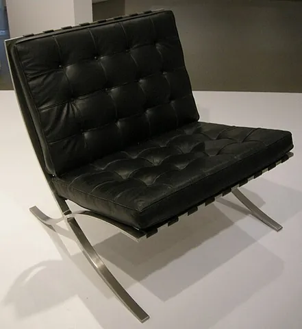barcelona chair: a chair, designed by Mies van der Rohe, that has a curved metal frame consisting of a gentle curve...