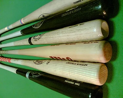 baseball bat: a long instrument, typically wood, metal, or plastic, which is swung to strike baseballs