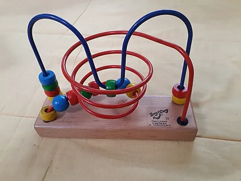 bead maze: a children's toy consisting of a set of rigid wires connecting parts of a solid base, serving as...