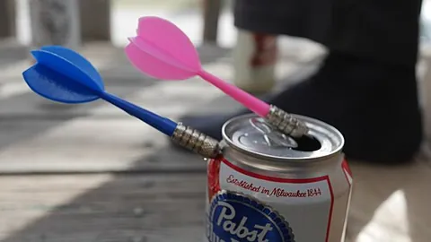 beer darts: a drinking game in which players place a beer can by their feet and take turns trying to hit their...