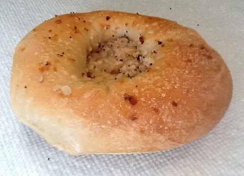 bialy: a flat bread roll topped with onion flakes. Instead of a hole like a bagel, it has a depression in...