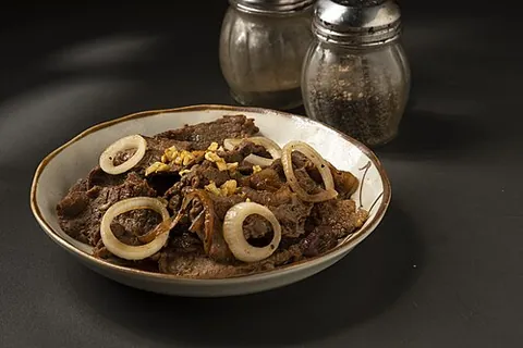 bistek: a Filipino dish consisting of thinly-sliced beefsteak braised in soy sauce, calamansi juice,...