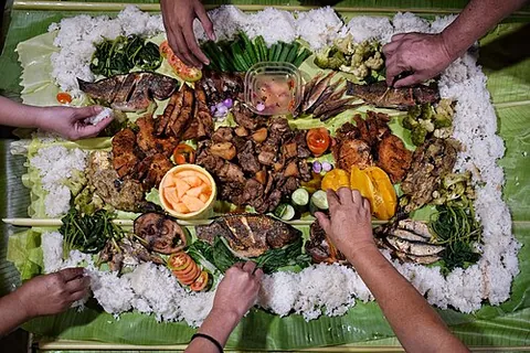 boodle fight: a large communal meal where food is placed directly on top of banana leaves across a long table...