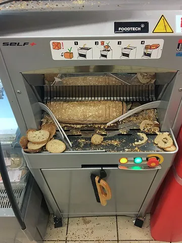 bread slicer: a kitchen or bakery instrument used to cut bread into equal thicknesses