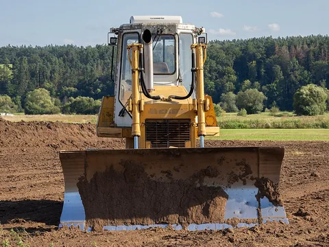 bulldozer: a tractor with caterpillar tracks and an attached blade for pushing earth and building debris for...