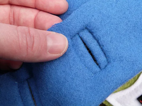 buttonhole: a hole through which a button is pushed to secure a garment or some part of one