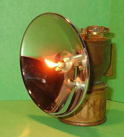 carbide lamp: a simple lamp that produces and burns acetylene (C₂H₂) created by the reaction of calcium carbide...