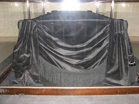 catafalque: a platform used to display or convey a coffin during a funeral, often ornate