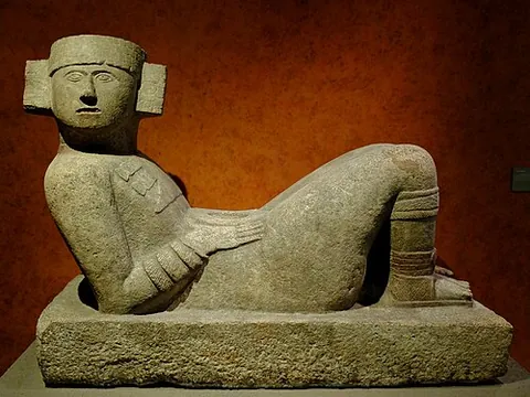 chacmool: a stylized, pre-Columbian Mesoamerican stone sculpture depicting a reclining male figure with the...