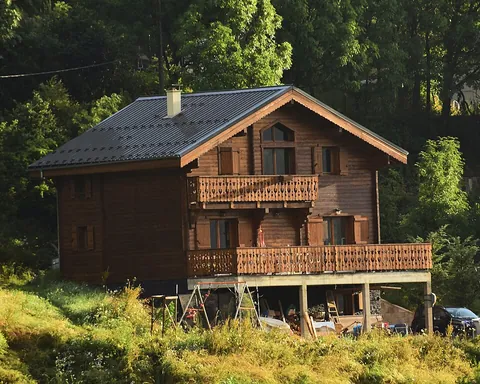 chalet: an alpine style of wooden building with a sloping roof and overhanging eaves