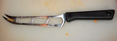 cheese knife: a type of knife used for cutting cheese, typically with a wide, curved blade with two prongs