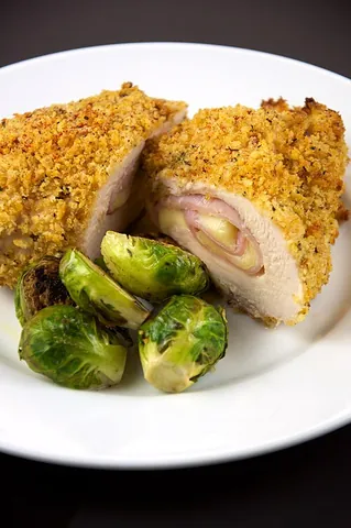 chicken cordon bleu: thin slices of chicken pressed together and breaded, with a filling of cheese and a ham slice...