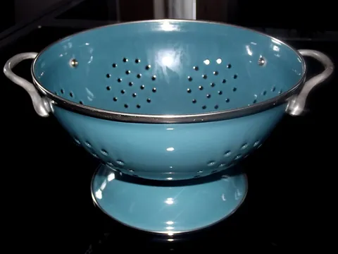 colander: a bowl-shaped kitchen utensil with holes in it used for draining food that has been cooking in...