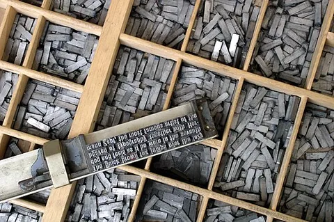 composing stick: a device used in printing with movable type to hold the type as it is being selected