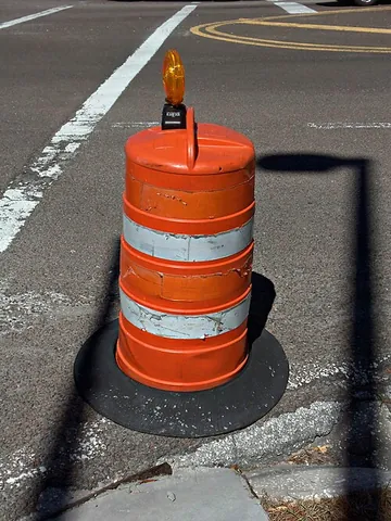 construction barrel: a usually striped cylindrical object used as a temporary traffic barrier or warning near...
