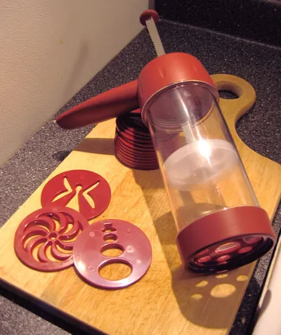 cookie press: a tool for making certain types of cookie, consisting of a cylinder with a plunger on one end, used...