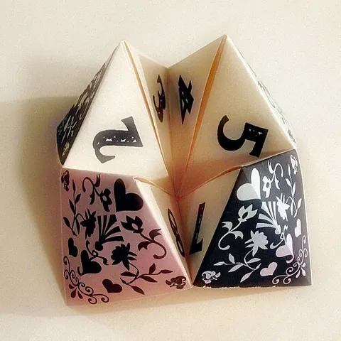 cootie catcher: a form of origami with hidden fortunes, activities, etc. written on the folds, and used mainly in...