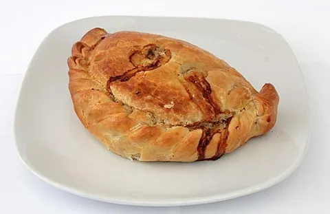 cornish pasty: a kind of meat pie, not made in a pie pan but with a large piece of folded-over pastry dough,...
