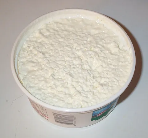 cottage cheese: a cheese curd product with a mild flavor that is drained but not pressed so some whey remains