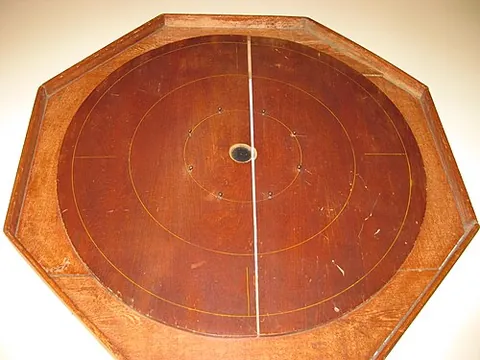 crokinole: a game, popular in Canada, in which wooden discs are flicked towards the centre of a circular board
