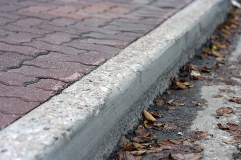 curb: a concrete margin along the edge of a road; a kerb (UK, Australia, New Zealand)