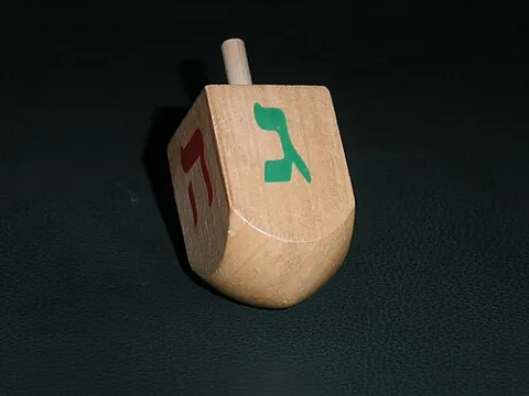 dreidel: a four-sided spinning top, inscribed with the four Hebrew letters נ (nun), ג (gimel), ה (hey), and...
