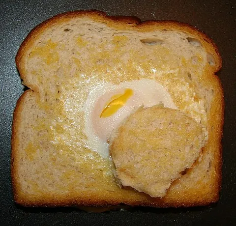 egg in a hole: an egg fried in a hole in a slice of bread