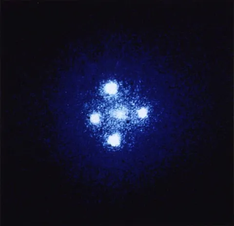 einstein cross: a quadruply replicated image of a quasar, in the configuration of a cross, surrounding a central...
