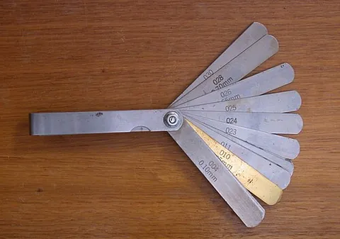 feeler gauge: a set of thin metal strips, of known thickness, used to measure a narrow gap such as by go/no-go...