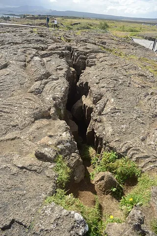 fissure: a long, narrow crack or opening made by breaking or splitting, especially in rock or earth