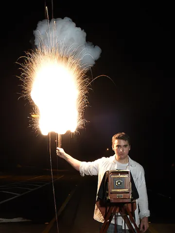 flashlamp: a kind of lamp that uses an electric current to start powder burning and produce a brief sudden...