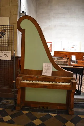 giraffe piano: a piano that is built like a grand piano on its side with the small end at the top, often with a...