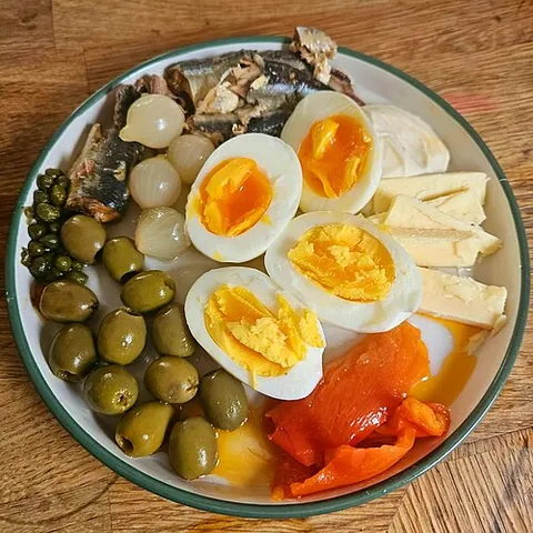 girl dinner: a simple, low-effort meal prepared without cooking from various tapas-like food items (cheese,...
