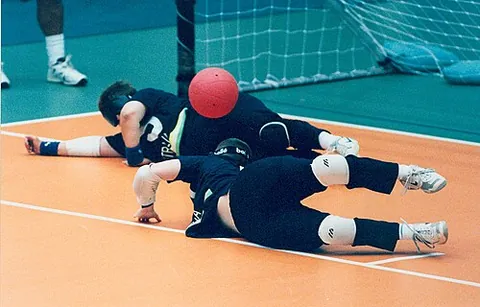 goalball: a ball game, designed for the blind, in which teams of three players attempt to throw a ball with...