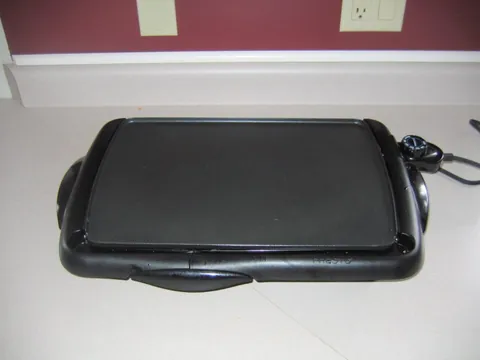 griddle: a stone or metal flat plate or surface on which food is fried or baked