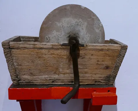 grindstone: an abrasive wheel for sharpening, polishing, or grinding