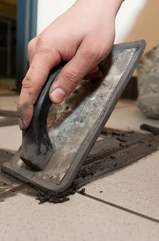grout: a thin mortar used to fill the gaps between tiles and cavities in masonry