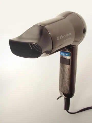 hair dryer: a handheld electric device for drying hair by blowing hot air on it