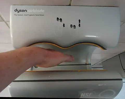 hand dryer: an electric-powered device in a restroom to dry hands with a stream of warm air