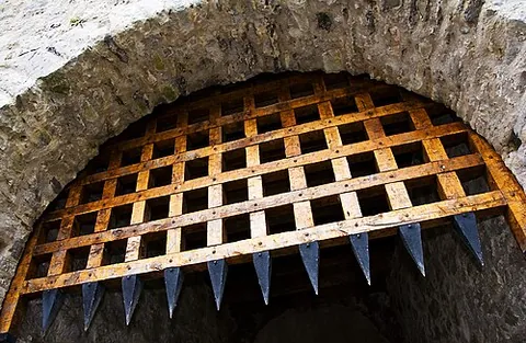 herse: a kind of gate or portcullis, having iron bars, like a harrow, studded with iron spikes, hung above...