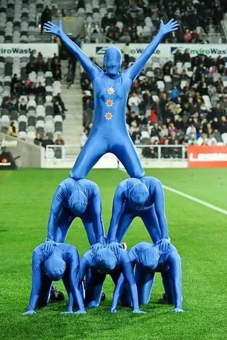 human pyramid: a tower made of people standing or kneeling on top of each other