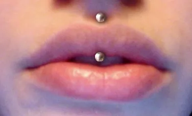 jestrum: a vertical philtrum piercing, placed vertically through the lip using a curved barbell so that both...