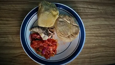 kenkey: a West African staple food made from a ball of boiled and fermented dough, usually maize, wrapped...