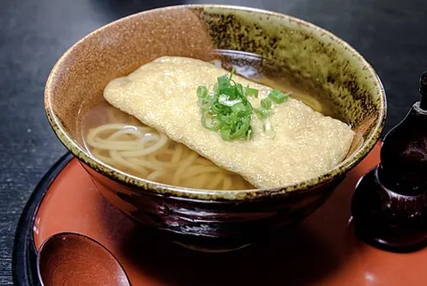 kitsune udon: japanese hot udon soup topped with seasoned fried tofu, and scallions